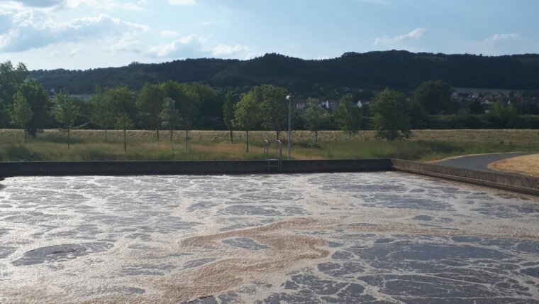 Ein mit Abwasser gefülltes Klärbecken vor der Landschaft des Saaletals